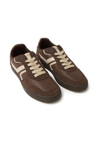 Sneaker marroni con una combinazione di tomaie in pelle e camoscio, dettagli beige, punta rotonda e lacci piatti. Perforazioni e suola in gomma.
