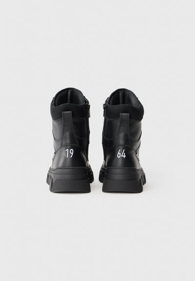 Czarne wysokie sneakersy z gładkiej skóry, z teksturowaną podeszwą, zamkiem błyskawicznym oraz białymi cyframi "19" i "64" na pięcie.