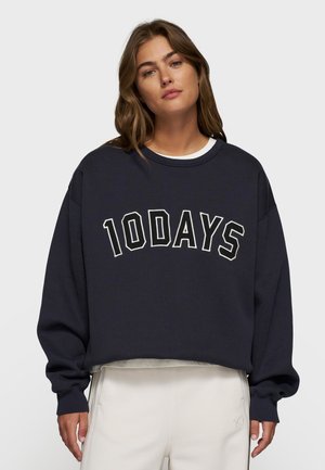 Felpa cropped blu navy con scritta bianca "10DAYS", colletto a girocollo a coste e maniche lunghe. Tessuto morbido con vestibilità comoda.
