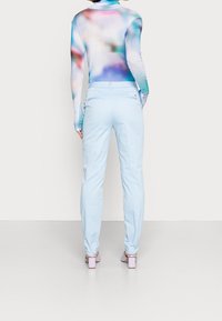 Pitkähihainen paita, jossa monivärinen abstrakti kuvio, yhdistetty vaaleansinisiin kapealahkeisiin housuihin ja laventelinvärisiin lohkokantaisiin kenkiin.