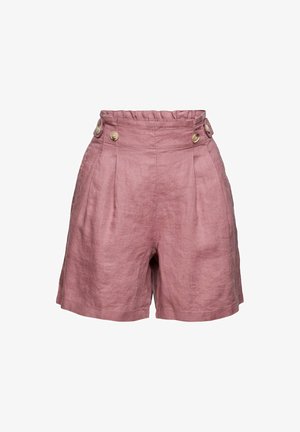Mujer con top de lino de manga corta y pantalones cortos en color malva, sosteniendo un bolso de cuero marrón y sandalias beige sobre un fondo blanco.