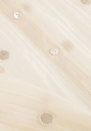 Beige stof met verticale gestructureerde strepen, parelmoeren knopen en ronde heldere pailletten in een gedoteerd patroon.