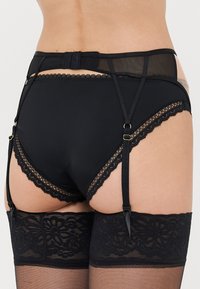 Black lingerie set with a high-waisted design. Features lace trim and adjustable straps, paired with black lace top stockings.
