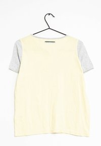 Kortärmad t-shirt med en kropp i citron-gul och grå ärmar. Mjuk tyg med rund halsringning. Hängande på en svart krok mot en vit bakgrund.