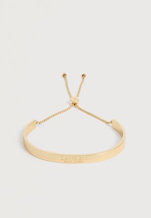Bracelet chaîne ajustable en or avec gravure "LAUREN RALPH LAUREN" sur une plaque métallique lisse.