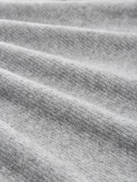 Tessuto grigio chiaro con una trama fine, caratterizzato da pieghe morbide e un motivo leggermente melangiato, che illustra un aspetto accogliente e caldo.