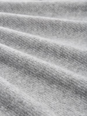 Lichtgrijze stof met een fijne textuur, met zachte plooien en een licht gemêleerd patroon, die een gezellige en warme uitstraling biedt.