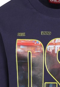 Felpa blu navy con una grande stampa grafica e dettagli gialli, con testo "DIESEL". Collo a girocotolo a coste e texture morbida.
