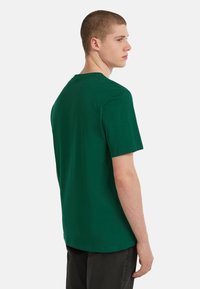 Grøn bomulds T-shirt med rund hals, korte ærmer og en afslappet pasform. Glat tekstur, ingen mønstre eller synlige detaljer.