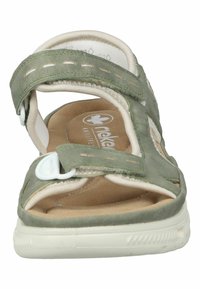 Sandalo verde in suede con cinturino in velcro, soletta imbottita color tan e suola in gomma bianca. Presenta cuciture e un logo sulla pianta.