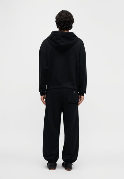 Μαύρο φούτερ με κουκούλα και τζόγκερ σετ από μαλακό ύφασμα. Το φούτερ διαθέτει μεγάλη κουκούλα, ενώ τα τζόγκερ έχουν ελαστική μέση και τσέπη.