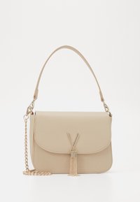 Beige fusk-läder väska med lockstängning, guld kedjesträng och tofsdetalj. Har 'V'-hardware på framsidan. Texturerad yta.