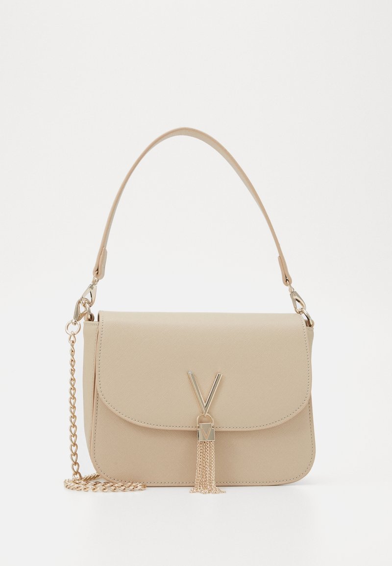 Beige fusk-läder väska med lockstängning, guld kedjesträng och tofsdetalj. Har 'V'-hardware på framsidan. Texturerad yta.