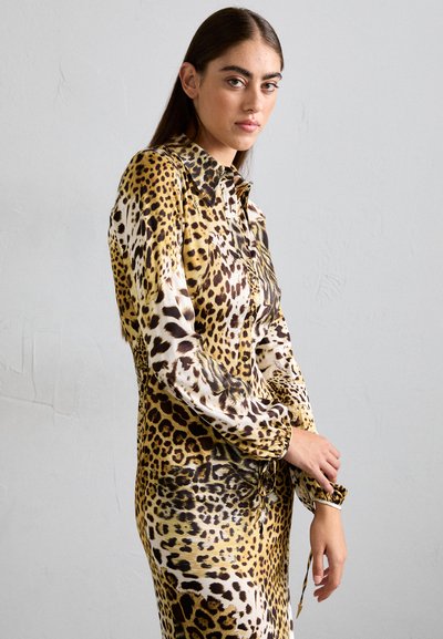 Leopard print dress featuring a collared neck, long sleeves, and a fitted silhouette, made of smooth, lightweight material in brown and yellow tones.
