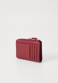 Rød lær lommebok med glidelås, med fire kortlommer og en teksturert overflate. Kompakt rektangulær form med detaljer i gulltone.