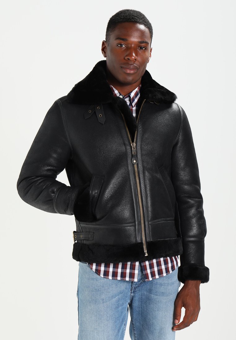 Chaqueta de cuero negra con cuello de piel, cierre de cremallera y bolsillos laterales. Presenta una textura suave y un diseño ajustado.