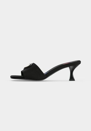 Μαύρο mule με ανοιχτή μύτη, χαμηλό καμπυλωτό τακούνι και φαρδιά λωρίδα με στρογγυλό μεταλλικό πόμολο.