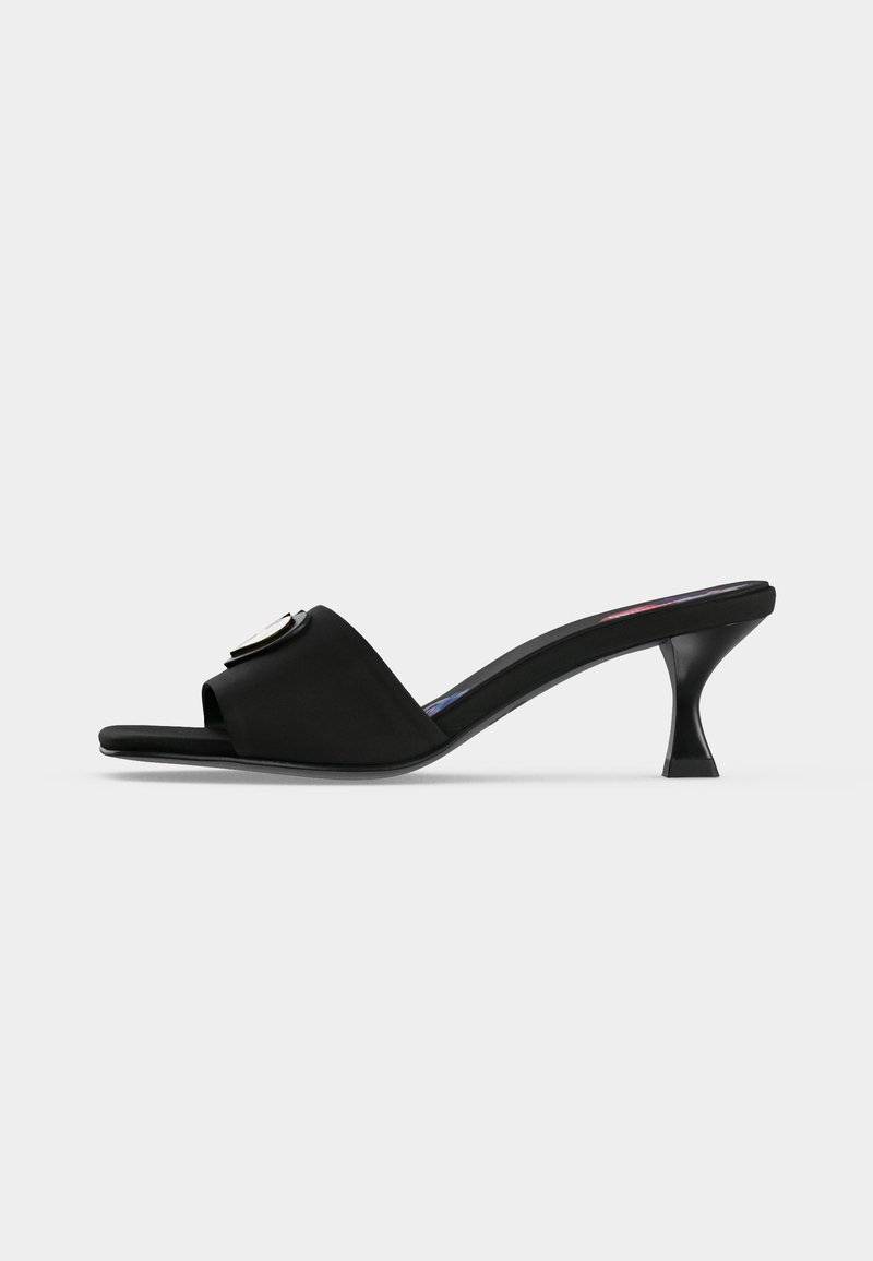 Μαύρο mule με ανοιχτή μύτη, χαμηλό καμπυλωτό τακούνι και φαρδιά λωρίδα με στρογγυλό μεταλλικό πόμολο.