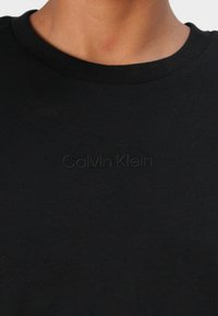 Svart bomulls t-skjorte med rund hals og brodert "Calvin Klein"-logo på forsiden. Glatt tekstur og klassisk passform.