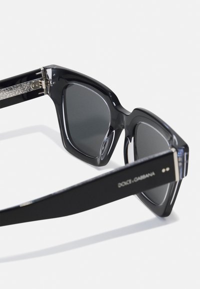 Black sunglasses with a bold cat-eye design, featuring dark lenses, glossy acetate frames, and metal accents on the arms.