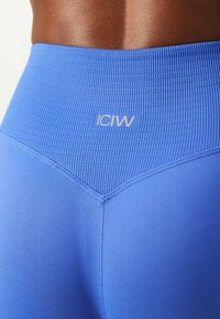 Blå högmidjade leggings med en texturerad midja, med en logotyp. Slät tyg med kontrasterande sömnadsdetaljer.