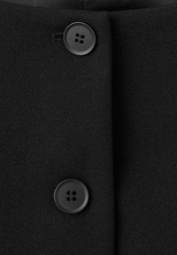 Tessuto nero che mostra una cucitura con due bottoni rotondi neri, ciascuno con quattro fori, su una superficie liscia e strutturata.