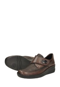 Zapatos de cuero marrón con una parte superior de tela texturizada, que cuentan con un cierre de correa ancha y una suela de goma texturizada. Botones decorativos sutiles adornan la correa.