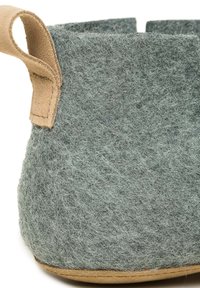 Grå plantekrukke med en struktureret overflade, afrundet form og et tan læderhåndtag. Bunden er lavet af glat brunt materiale.