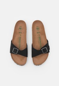 Black sandals with a wide strap and metal buckle, featuring a brown contoured footbed and textured rubber outsole. Size 37.