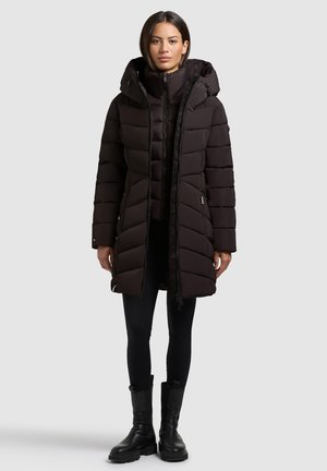 Black puffer coat with a hood, featuring a zip closure, quilted design, and elastic cuffs. Worn over black leggings and chunky black boots.