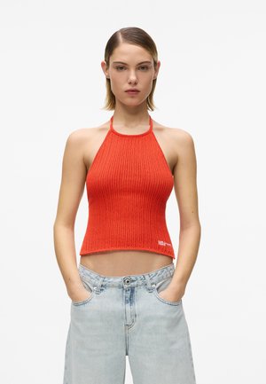 Rdeč rebrast zgornji del obleke na trakce s krajšim dizajnom in odprtimi hrbtom, kombiniran z svetlo modrimi ohlapnimi jeans hlačami z sprednjimi žepi in subtilnim pranjem.