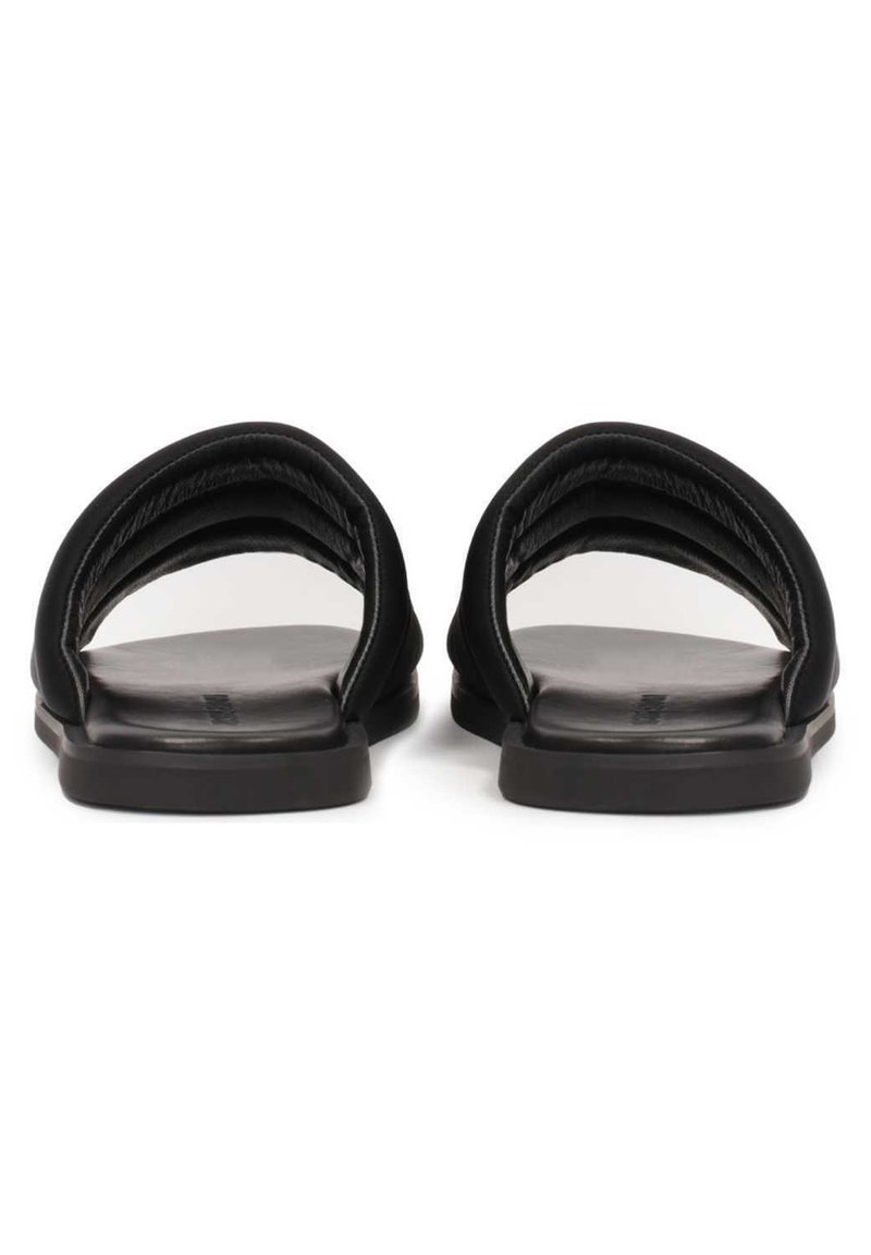 Sandales noires à glissière avec deux sangles courbées, texture en cuir lisse, semelle plate et un design minimaliste sans accents supplémentaires.