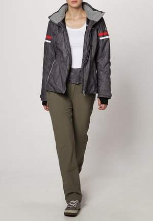 Grau strukturierte Jacke mit grauem Kapuzen, roten und weißen Streifen an den Ärmeln, kombiniert mit olivgrünen Hosen und grauen Turnschuhen.