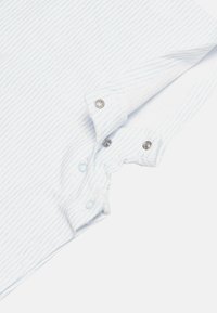 Camisa blanca con rayas azul claro, que presenta un cuello abotonado, cierres de presión y una tela de textura suave.