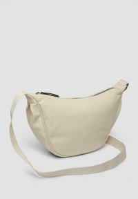 Kremowa torba na ramię wykonana z materiału o teksturowanej powierzchni, z zamkiem błyskawicznym i płaskim, regulowanym paskiem. Krzywoliniowy kształt i akcenty szwów.
