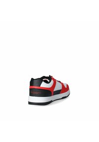 Scarpa da ginnastica rossa, bianca e nera con una texture in pelle liscia, design a profilo basso, suola spessa bianca e dettaglio del logo sul lato.