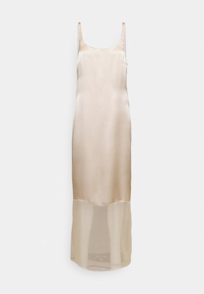 Σατέν μπεζ φόρεμα slip με λεπτές τιράντες, εφαρμοστή σιλουέτα και διαφανές κάτω μέρος που εκτείνεται μέχρι το μέσο της γάμπας.