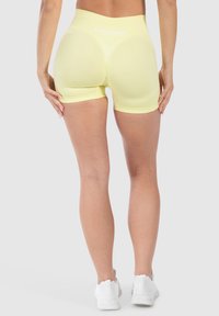 Geel sportieve shorts met een hoge tailleband, voorzien van een gladde textuur en een contrasterend wit logo aan de achterkant, strakke pasvorm.