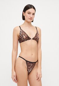 Bikini set met luipaardprint, bestaande uit een triangeltop met dunne bandjes en een zwarte rand, vergezeld van bijpassende low-rise slips.