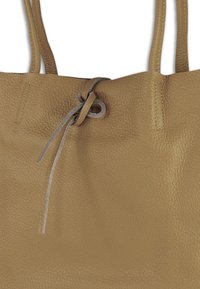 Tan lederen shopper met een getextureerd oppervlak, voorzien van een trekkoordsluiting en twee schouderbanden. Eenvoudig en functioneel ontwerp.