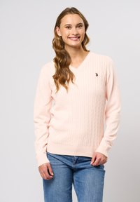 Lichtroze v-hals trui met een textuur van kabelbreipatroon. Lange mouwen en geribbelde zoom. Klein geborduurd logo op de borst. Te combineren met jeans.