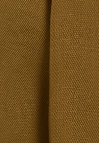 Tejido texturizado en un tono amarillo mostaza, con un patrón acanalado diagonal. La superficie parece duradera y está tejida de manera compacta.