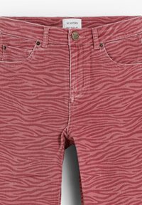 Vaqueros de mezclilla rojos con un sutil patrón de rayas de cebra, diseño de cinco bolsillos y cierre de botón metálico con un motivo de calavera.