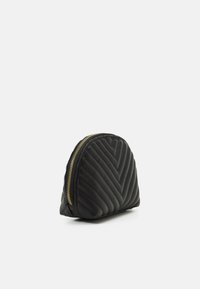 Pochette nera trapuntata a forma di mezza luna, con una zip dorata e motivo a spina di pesce sulla superficie per una maggiore texture.