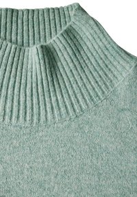 Mintgrön tröja med hög, ribbad hals och mjukt, strukturerat stickat tyg. Tyget har ett subtilt melerat mönster.