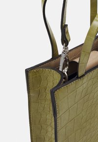 Borsa in pelle verde con texture a coccodrillo e rifiniture nere, dotata di manici doppi e chiusura con hardware silver, caratterizzata da un design strutturato.