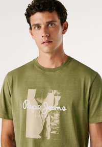 Olijfgroene katoenen t-shirt met een ronde hals en een frontgrafiek met de tekst "Pepe Jeans LONDON" in het wit.