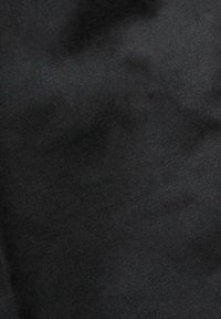 Tissu noir avec une texture subtile et des plis, montrant de légères variations de teinte.