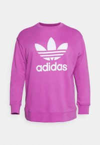 Lila crewneck sweatshirt med långa ärmar som har en stor vit Adidas trefoil-logotyp och text på framsidan.