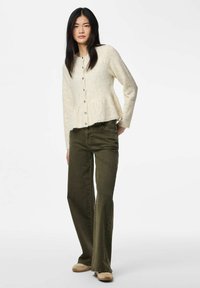 Cardigan en tricot ivoire à la coupe évasée, doté d'un devant boutonné et d'un tissu texturé, associé à un jean évasé vert olive et des chaussures tan.